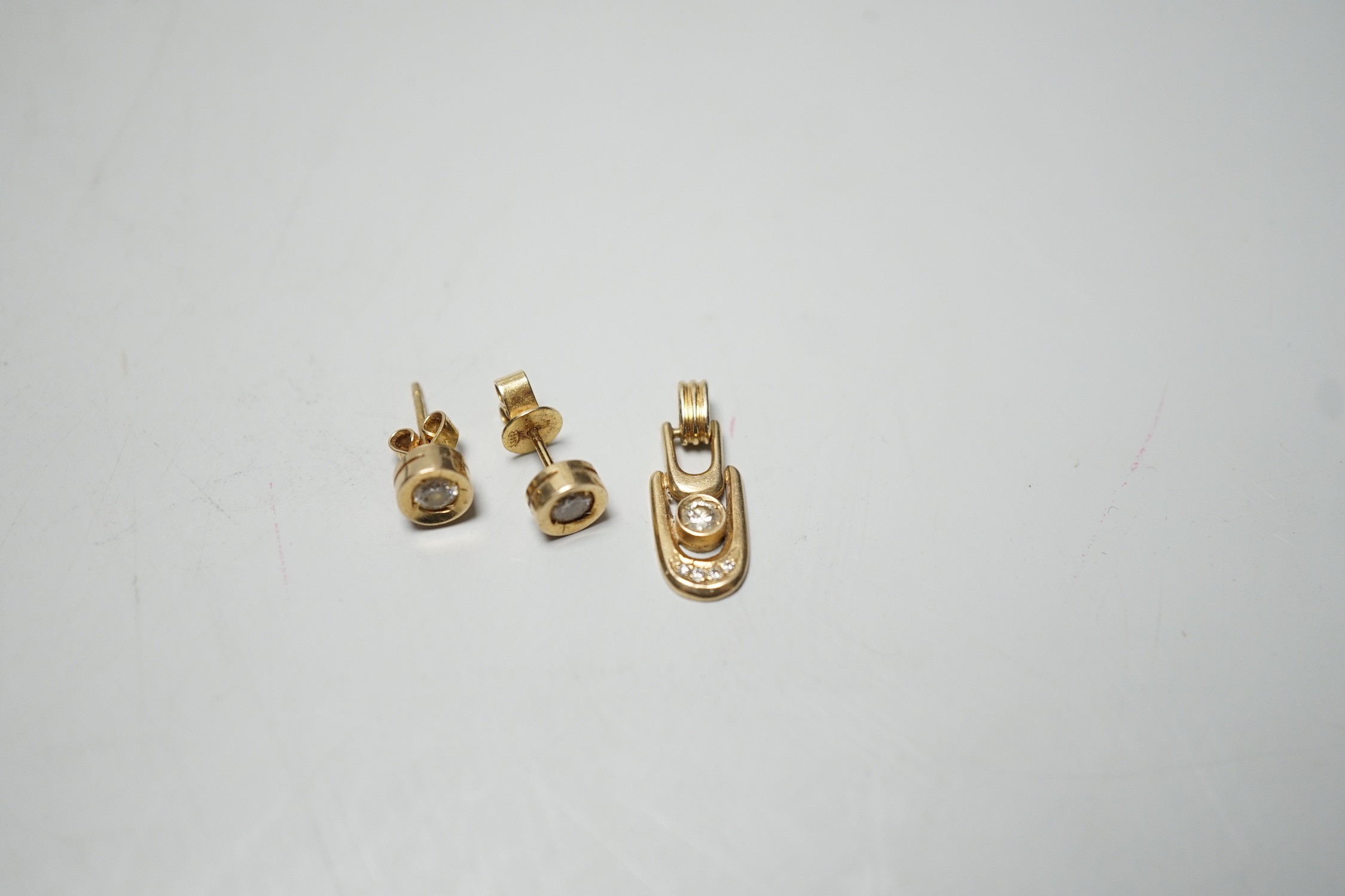 A modern pair of 585 yellow metal and solitaire diamond set ear studs, 6mm and a matching pendant, gross weight 3.9 grams.